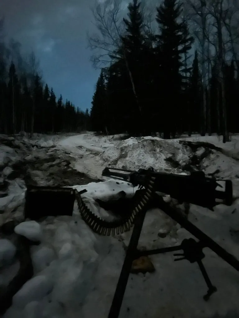 A tripod-mounted M2-style heavy machine gun positioned in a snowy clearing at dusk, surrounded by spruce treeline.